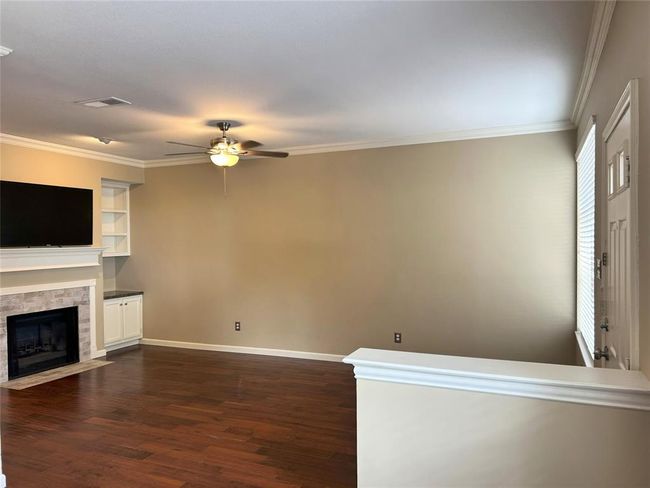This spacious den has wood burning fireplace, crown molding, a ceiling fan and built in bookshelves. | Image 14