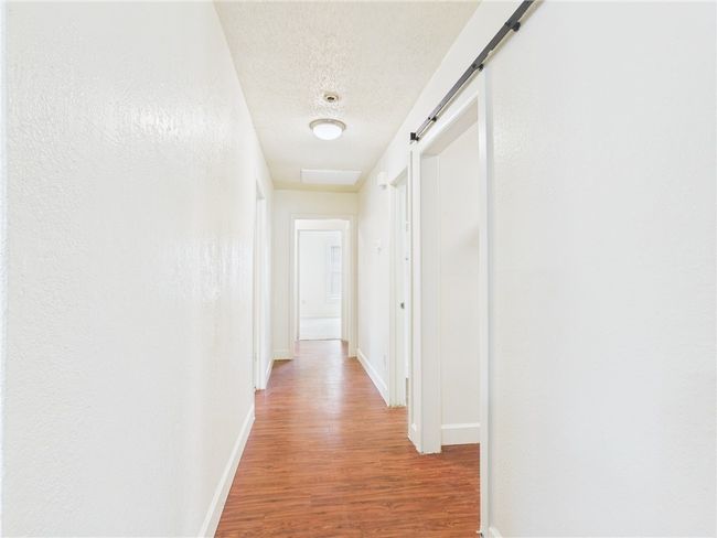 Hallway with wood finished floors, a textured ceiling, and a barn door | Image 8