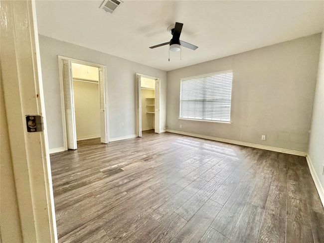Unfurnished bedroom with wood finished floors, two closets, and a ceiling fan | Image 25