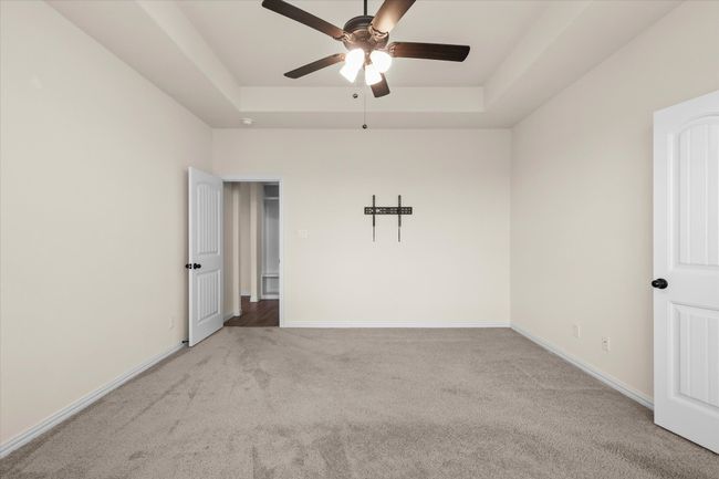 Carpeted empty room with a raised ceiling and a ceiling fan | Image 15