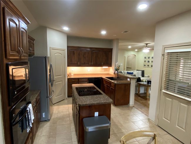 Kitchen featuring a peninsula, a sink, dark brown cabinets, ceiling fan, and black appliances | Image 13