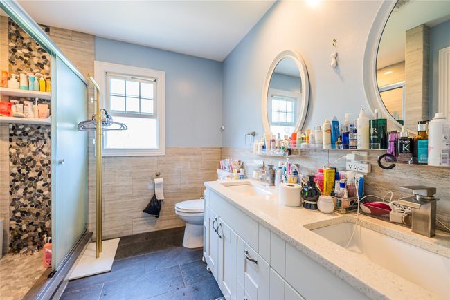 Full bath with tile walls, a stall shower, toilet, double vanity, and tile patterned floors | Image 12