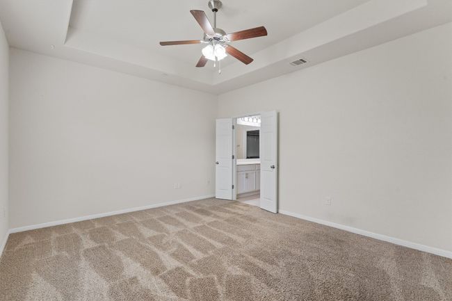 Spare room featuring light carpet, a raised ceiling, ceiling fan, and baseboards | Image 15
