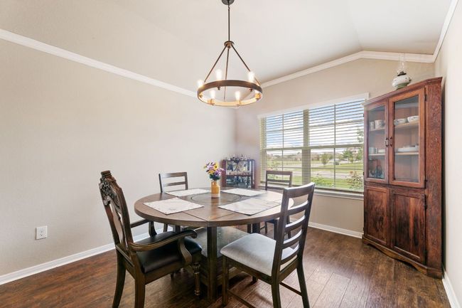 Dining room with crown molding, an inviting chandelier, vaulted ceiling, and dark wood finished floors | Image 6