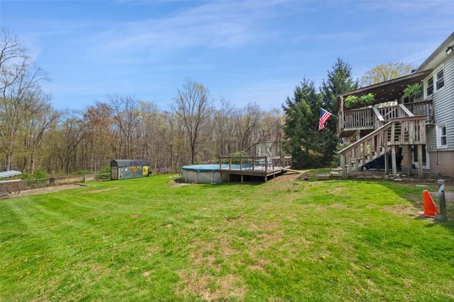 View of yard featuring a covered pool, a wooden deck, and stairs | Image 33