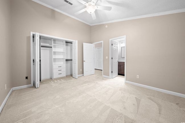 Unfurnished bedroom with a ceiling fan, visible vents, light colored carpet, baseboards, and ornamental molding | Image 13