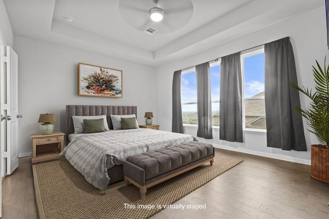 Bedroom with a tray ceiling, wood finished floors, baseboards, and a ceiling fan | Image 18