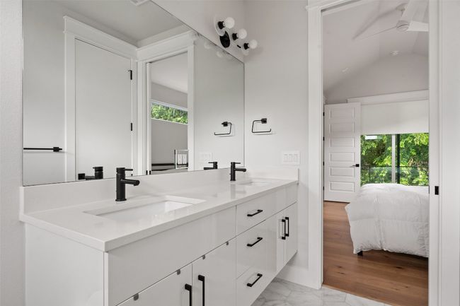 Full bath featuring ensuite bath, double vanity, ceiling fan, vaulted ceiling, and marble tile flooring | Image 16