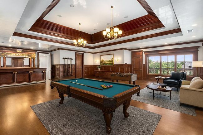 Playroom with a raised ceiling, crown molding, a chandelier, billiards, and a wainscoted wall | Image 30