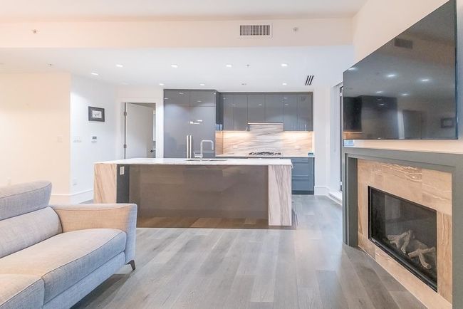Kitchen with light wood-style flooring, a sink, visible vents, backsplash, and modern cabinets | Image 7