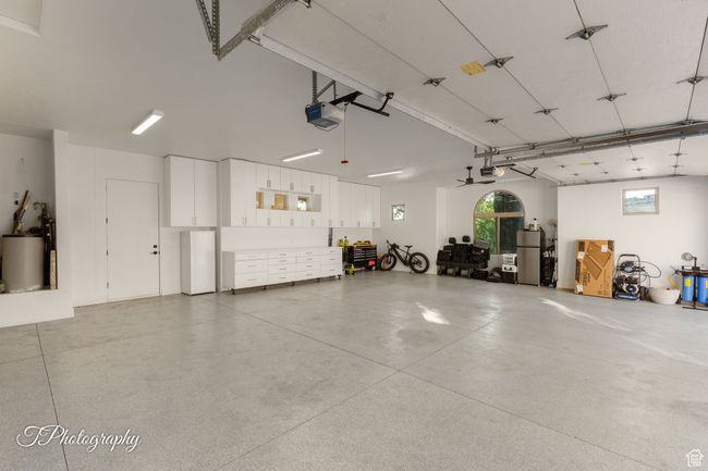 Garage featuring a garage door opener, freestanding refrigerator, and water heater | Image 48