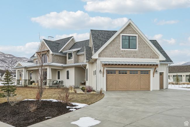 Shingle-style home with an attached garage, a standing seam roof, driveway, and board and batten siding | Image 52
