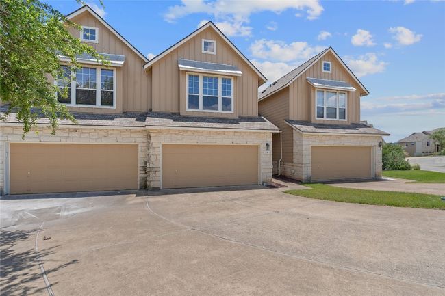 View of property with stone siding, board and batten siding, concrete driveway, and an attached garage | Image 6