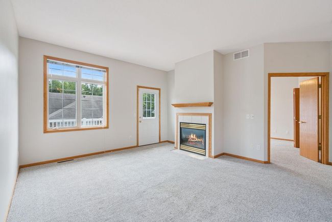 Main level living room with newer carpet, cozy natural gas fireplace, door leading out to large deck (28x10) | Image 14