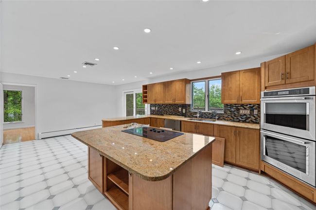Kitchen featuring open shelves, stainless steel double oven, baseboard heating, light floors, and brown cabinets | Image 10