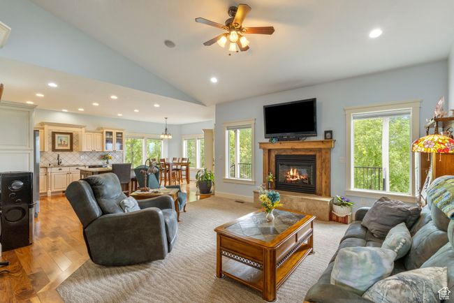 Living area with recessed lighting, healthy amount of natural light, vaulted ceiling, a glass covered fireplace, and a ceiling fan | Image 12