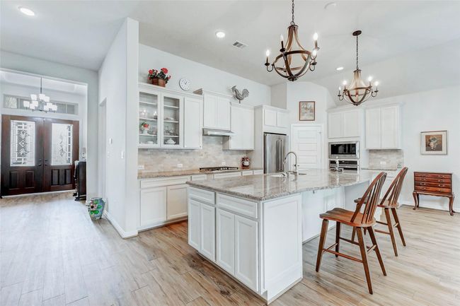 The chef’s kitchen is the heart of the home, centered around a generous island with a breakfast bar—both a stylish focal point and a functional space for meal prep and casual dining. | Image 5