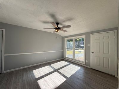 Unfurnished room featuring lofted ceiling, ceiling fan, a textured ceiling, and dark hardwood / wood-style flooring | Image 3