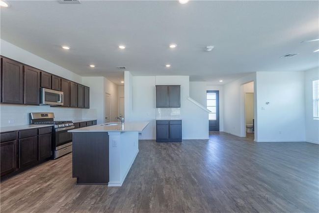 Kitchen with appliances with stainless steel finishes, dark wood finished floors, an island with sink, dark brown cabinets, and light countertops | Image 14