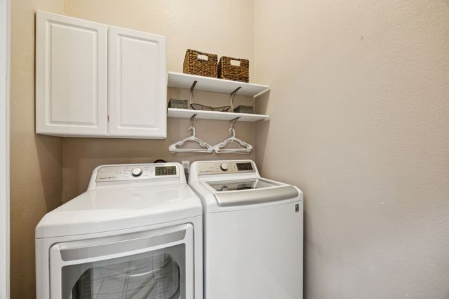 Efficiency meets organization in this dedicated laundry space with upper cabinets, open shelving, and a hanging rack—tucked conveniently near the main living areas. | Image 28