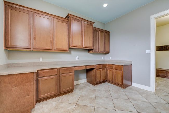 Spacious Laundry room with built-ins, light countertops, light tile patterned floors, and wood cabinetry | Image 15