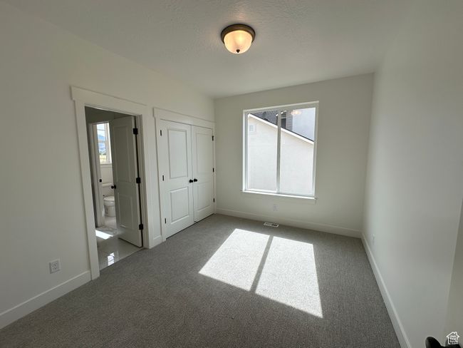 Unfurnished bedroom featuring carpet floors, ensuite bathroom, a textured ceiling, and a closet | Image 19