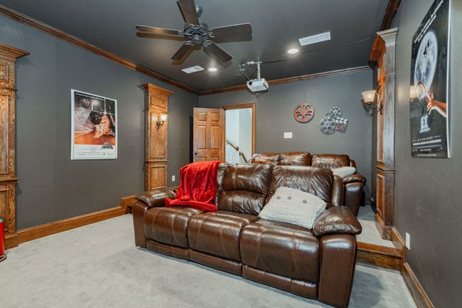 Carpeted cinema featuring ceiling fan, visible vents, baseboards, and ornamental molding | Image 30