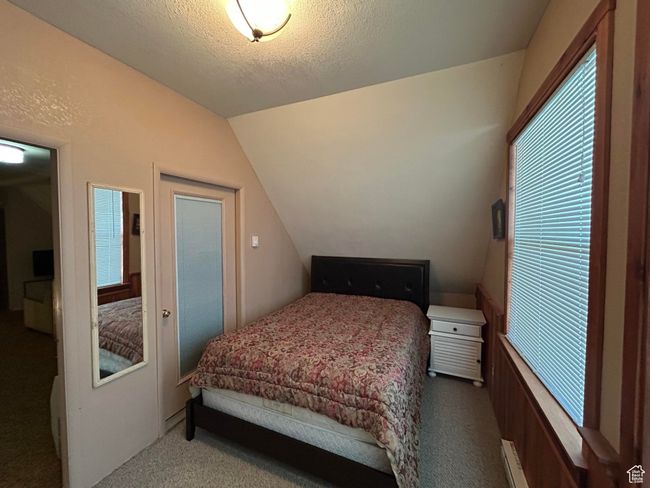 Carpeted bedroom featuring vaulted ceiling and a textured ceiling | Image 22