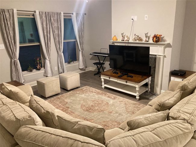 Living room with baseboards, wood finished floors, and a fireplace | Image 4