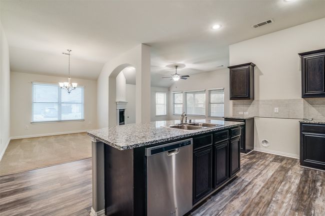 Kitchen featuring dishwasher, ceiling fan, wood finished floors, light stone counters, and open floor plan | Image 9