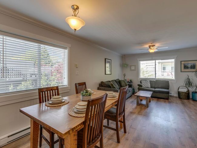 Dining room with a baseboard heating unit, ceiling fan, crown molding, and light wood-style flooring | Image 7