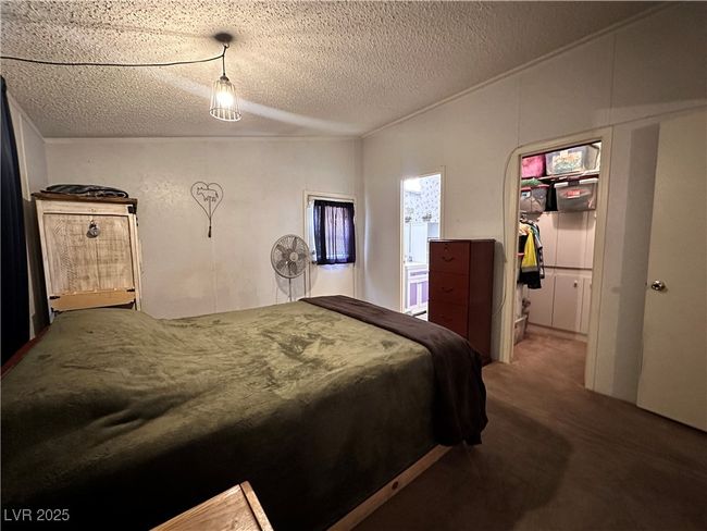 Bedroom with a textured ceiling, a walk in closet, and carpet | Image 13