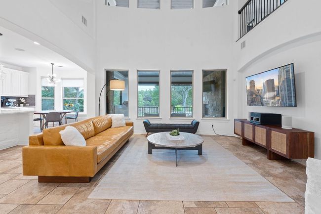 Living room featuring a chandelier, a towering ceiling, and light stone finish flooring | Image 32