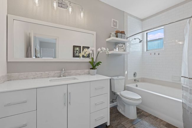Bathroom featuring vanity, shower / bathtub combination with curtain, and wood finished floors | Image 18