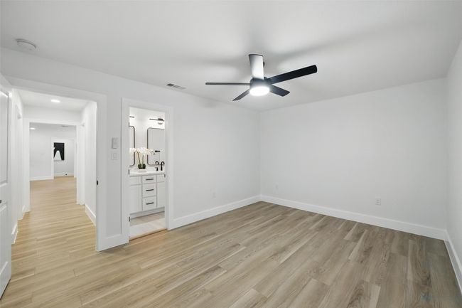 Unfurnished bedroom with light wood-type flooring, baseboards, ensuite bath, ceiling fan, and recessed lighting | Image 29