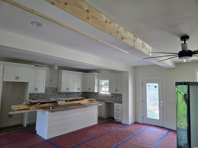 Kitchen featuring decorative backsplash, ceiling fan, white cabinets, a kitchen island, and baseboards | Image 8