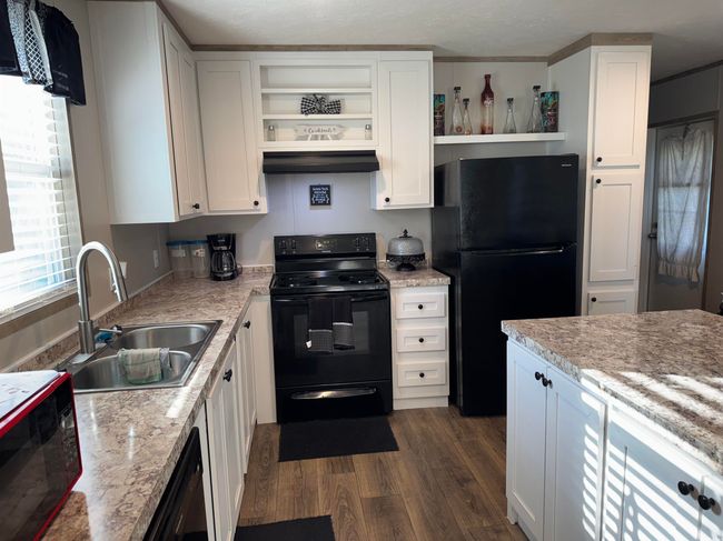Kitchen with black appliances, open shelves, custom range hood, and dark wood-type flooring | Image 5
