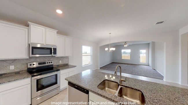 Kitchen featuring appliances with stainless steel finishes, a sink, decorative backsplash, white cabinets, and light stone countertops | Image 7