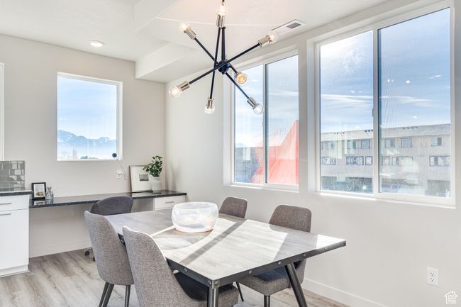 Dining area featuring a chandelier, light wood-style flooring, and baseboards | Image 6