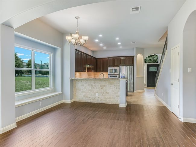 A spacious dining area looks out upon a lush green space. | Image 11