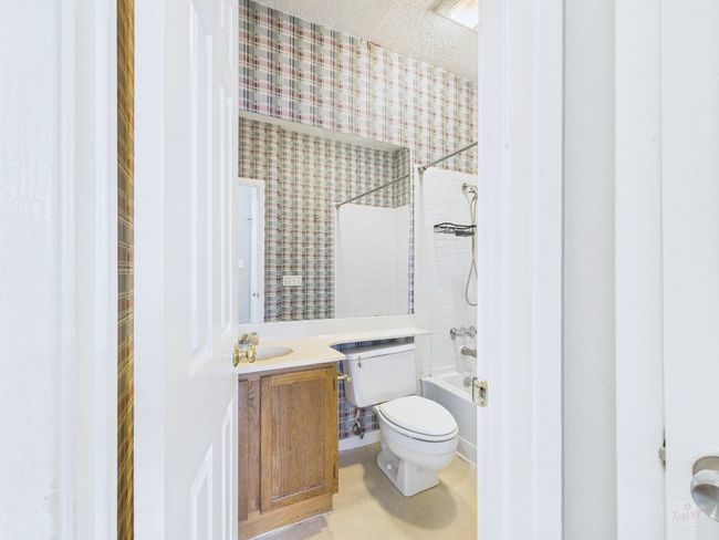 Bathroom with wallpapered walls, vanity, washtub / shower combination, and a textured ceiling | Image 31