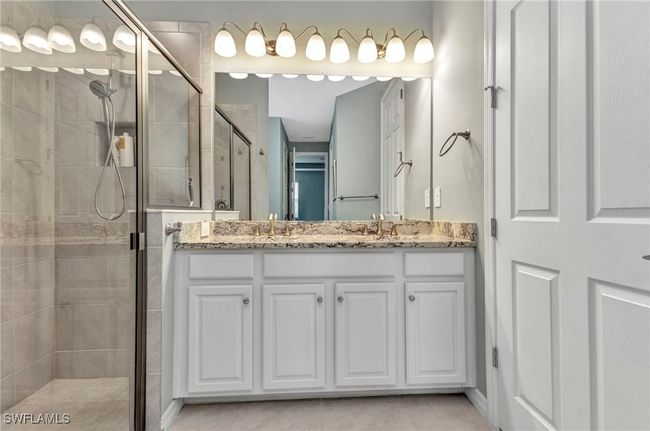 Full bathroom featuring a double sink, tile patterned flooring, a shower stall, and vanity | Image 37
