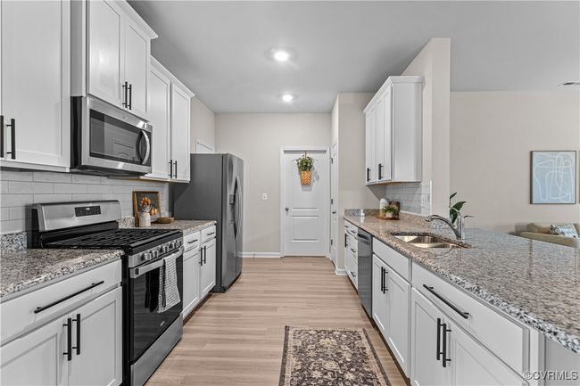 Kitchen with appliances with stainless steel finishes, a sink, light wood-type flooring, decorative backsplash, and baseboards | Image 12
