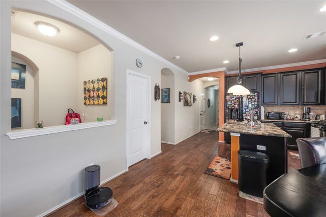 Kitchen featuring arched walkways, black fridge, dark wood-style floors, crown molding, and tasteful backsplash | Image 12