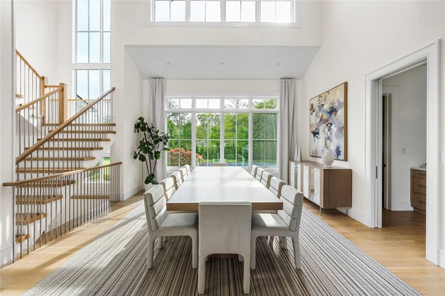 Dining room featuring a towering ceiling, healthy amount of natural light, light wood-type flooring, and baseboards | Image 7