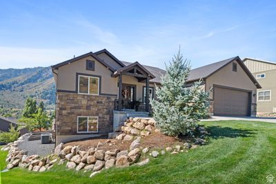 View of front of home with a mountain view, a front lawn, central AC unit, and a garage | Image 2