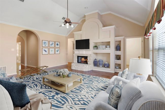 Living area featuring arched walkways, ceiling fan, a brick fireplace, wood finished floors, and baseboards | Image 23