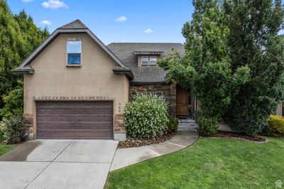 View of front of property featuring a two car garage and lovely front lawn with mature trees. | Image 1