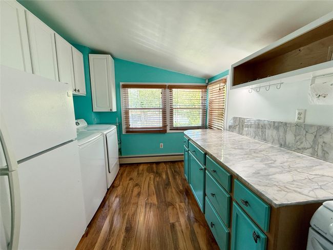 Empty room with a baseboard heating unit, wood finished floors, a ceiling fan, and baseboards | Image 4