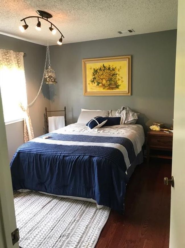 Bedroom with wood finished floors, rail lighting, and a textured ceiling | Image 12